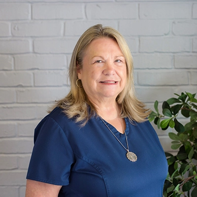 Carolyn Matherne smiling in blue scrubs.
